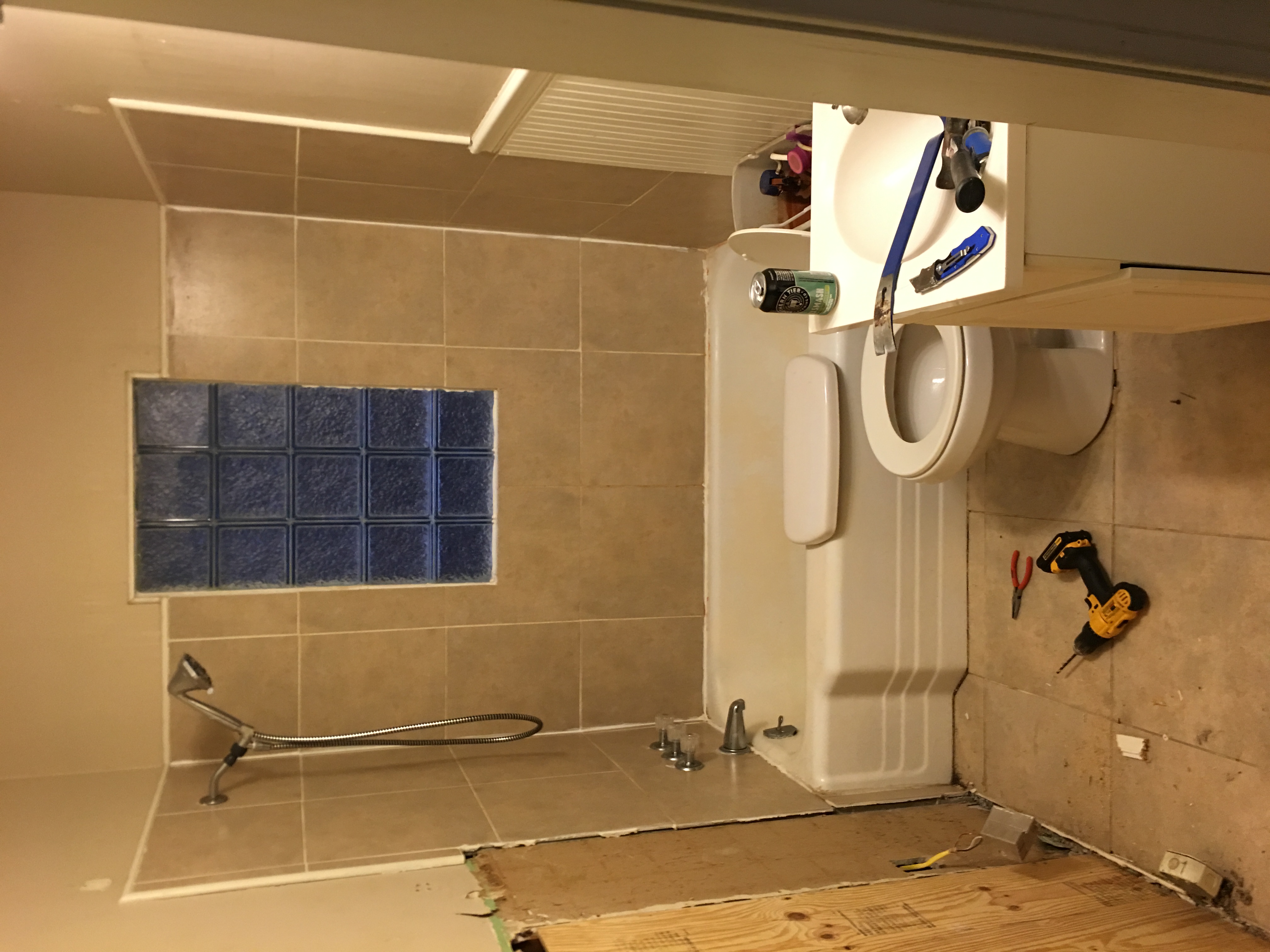 Bathroom before — original dated bathroom with tile tub surround and glass-block window