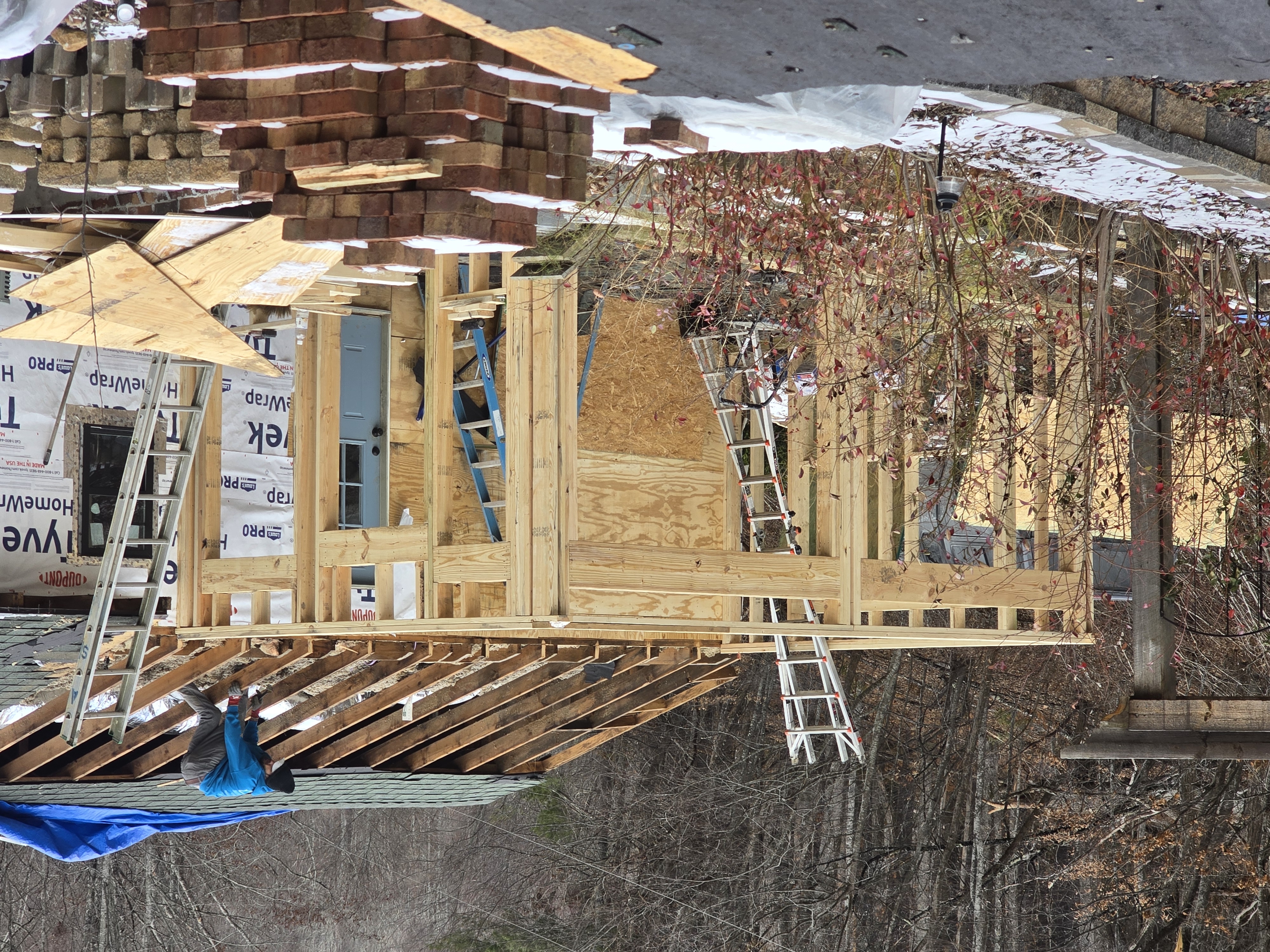Exterior rebuild in progress — reframed walls and new roof rafters