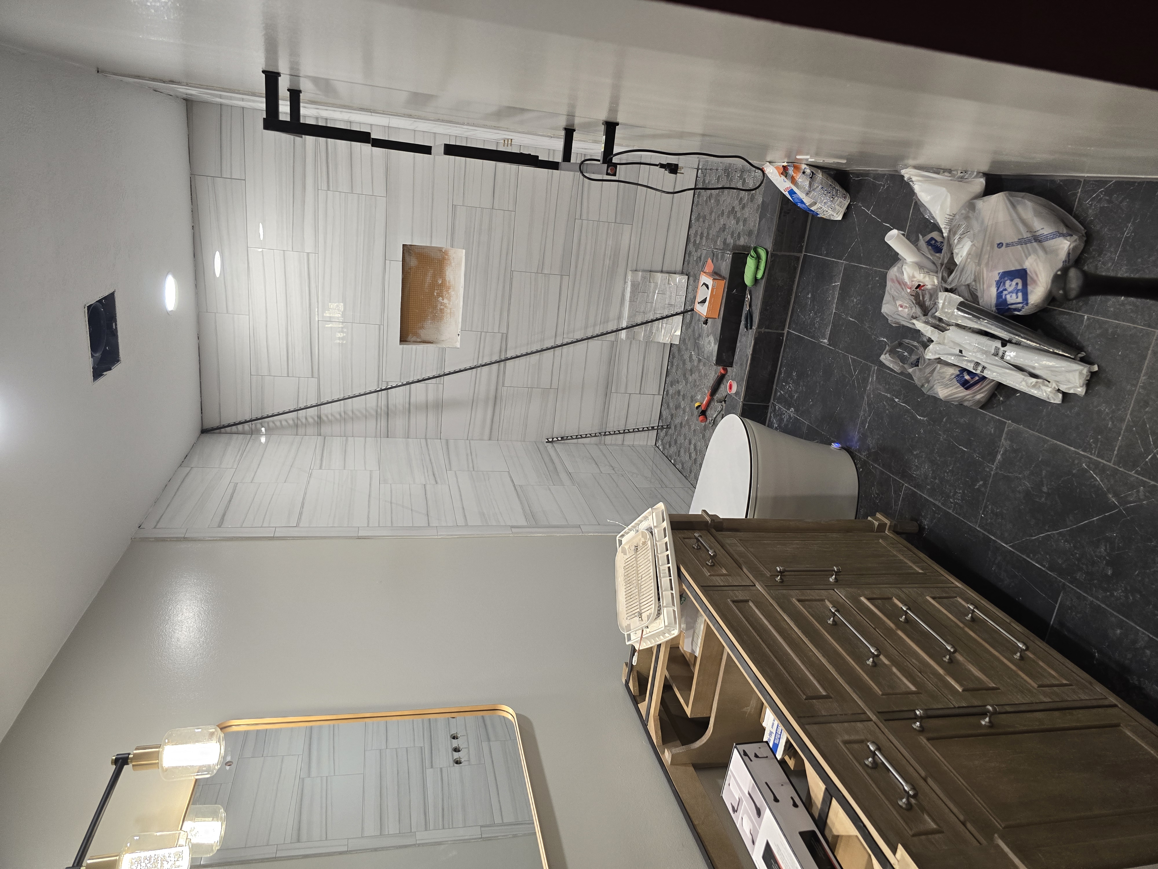 Walk-in shower in progress — vanity, toilet, and fixtures going in