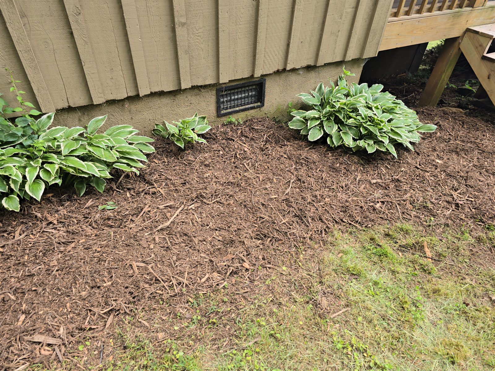 Refreshed planting beds with fresh mulch, river-rock edging, and new plantings