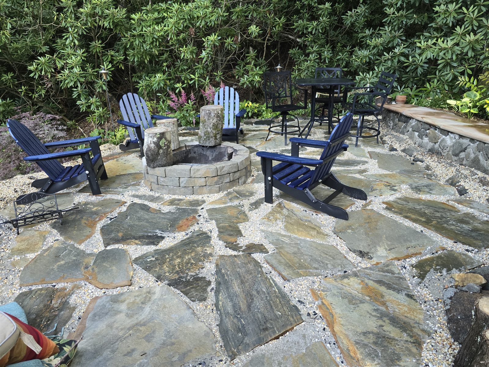Finished flagstone fire-pit patio with stacked-stone retaining wall and bench